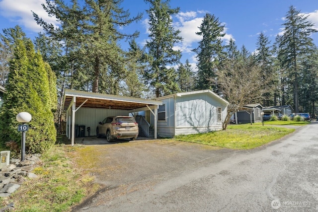 exterior space featuring aphalt driveway, a carport, and a front yard