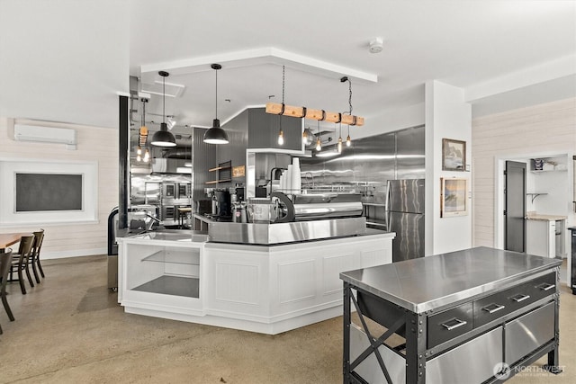 kitchen with decorative light fixtures, wood walls, concrete flooring, a wall unit AC, and stainless steel counters