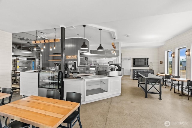 kitchen with finished concrete floors, hanging light fixtures, and white cabinetry