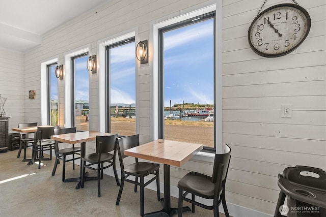 dining area featuring wooden walls and concrete flooring