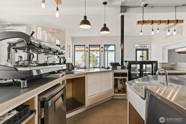 kitchen with hanging light fixtures, a sink, speckled floor, and stainless steel counters