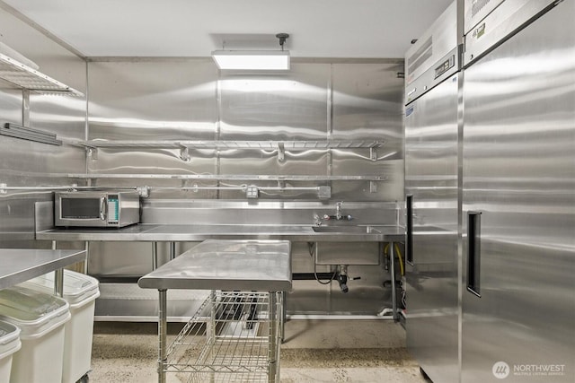 kitchen featuring stainless steel countertops, appliances with stainless steel finishes, and speckled floor