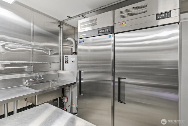 kitchen with gas water heater, stainless steel counters, and a sink