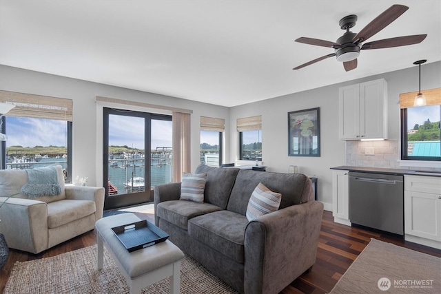 living room with dark wood finished floors, ceiling fan, and a water view