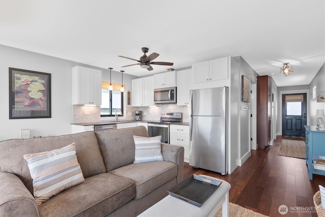 living area with dark wood-type flooring and a ceiling fan