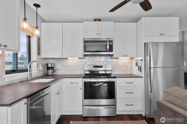 kitchen featuring dark countertops, backsplash, stainless steel appliances, and a ceiling fan