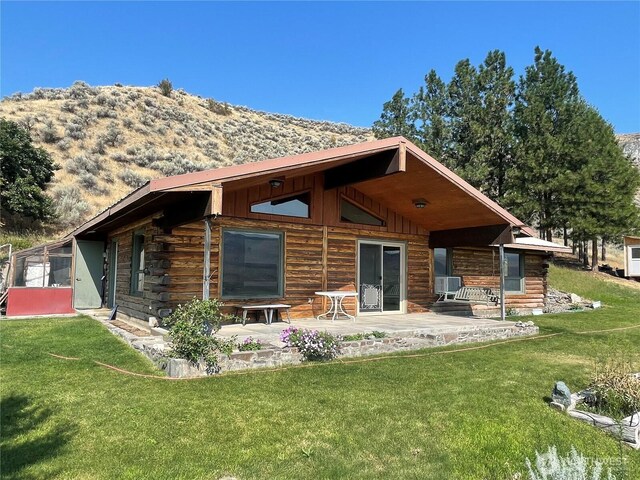 back of property featuring log exterior, a yard, and a patio