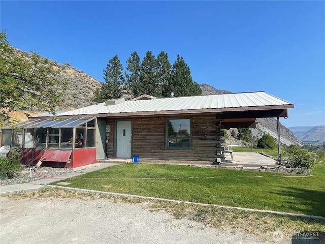 view of front of house with a front lawn, log siding, a mountain view, and metal roof