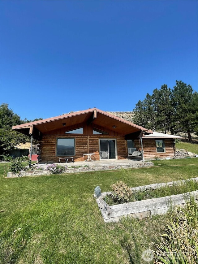 back of property with a patio area, log exterior, and a yard