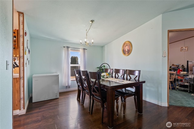 dining area featuring lofted ceiling, a notable chandelier, wood finished floors, and baseboards