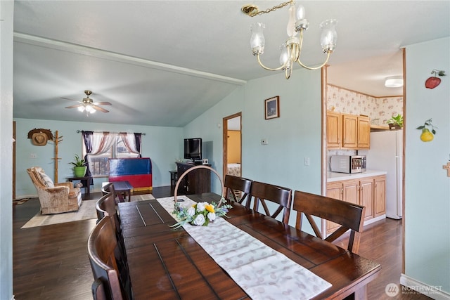 dining space with baseboards, ceiling fan with notable chandelier, dark wood finished floors, and vaulted ceiling