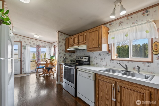 kitchen featuring wallpapered walls, under cabinet range hood, light countertops, white appliances, and a sink