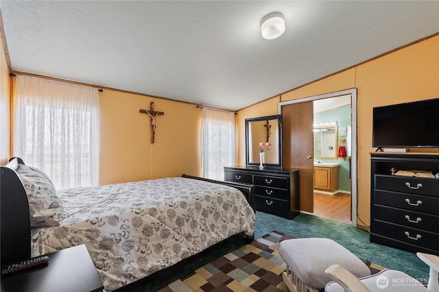 carpeted bedroom featuring lofted ceiling and ensuite bath