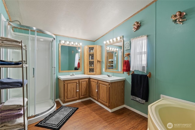 full bathroom featuring a stall shower, a sink, a textured ceiling, wood finished floors, and lofted ceiling