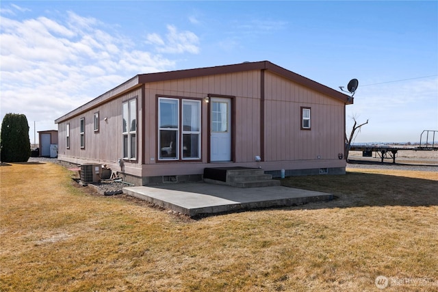 rear view of property featuring central AC unit, entry steps, crawl space, a patio area, and a lawn