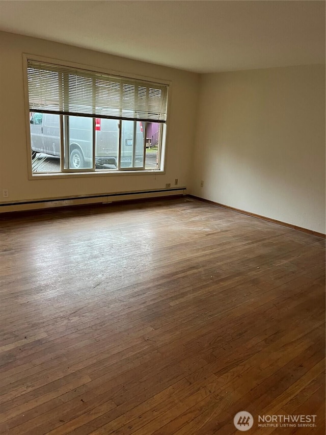 empty room featuring a baseboard radiator, baseboards, and hardwood / wood-style floors