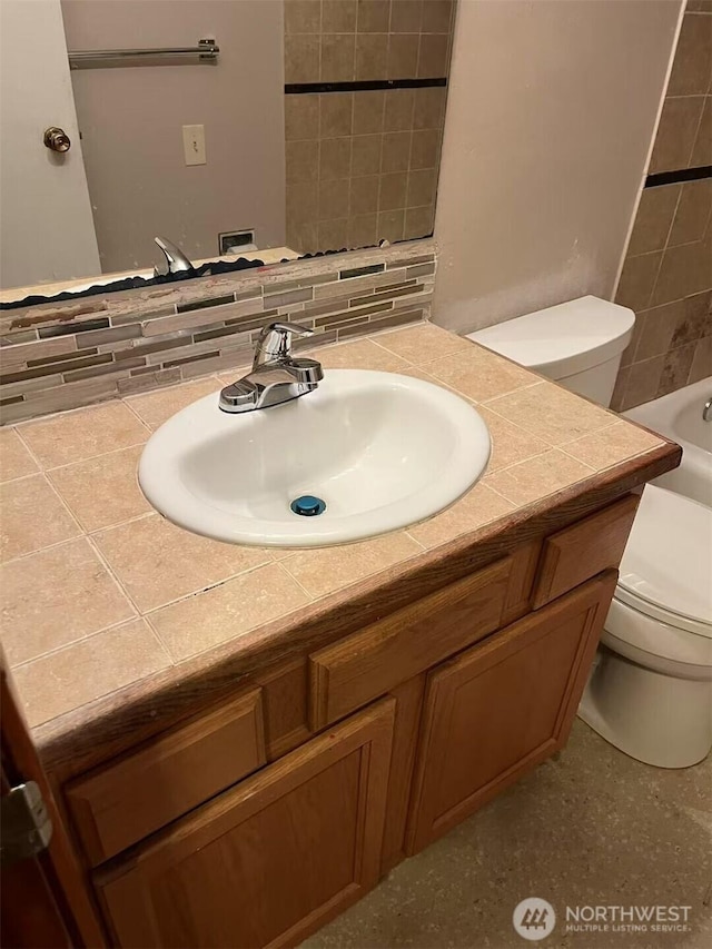 full bathroom with a tub, backsplash, vanity, and toilet