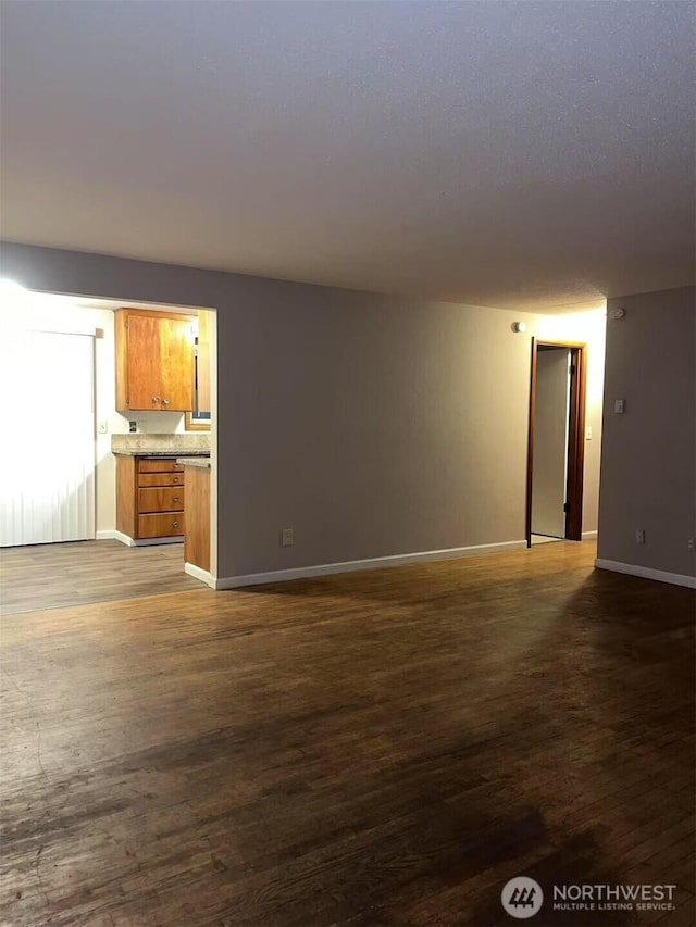 unfurnished living room with dark wood finished floors and baseboards