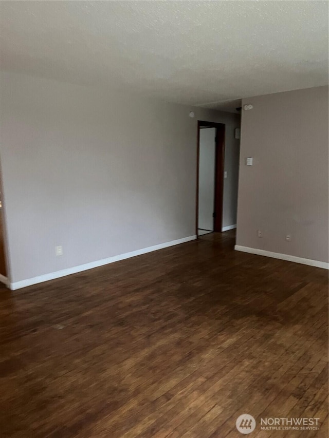 empty room with baseboards, dark wood-type flooring, and a textured ceiling