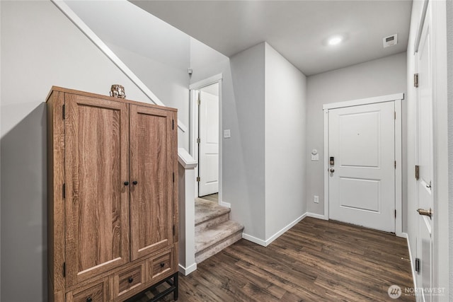 foyer with visible vents, stairs, dark wood-type flooring, and baseboards