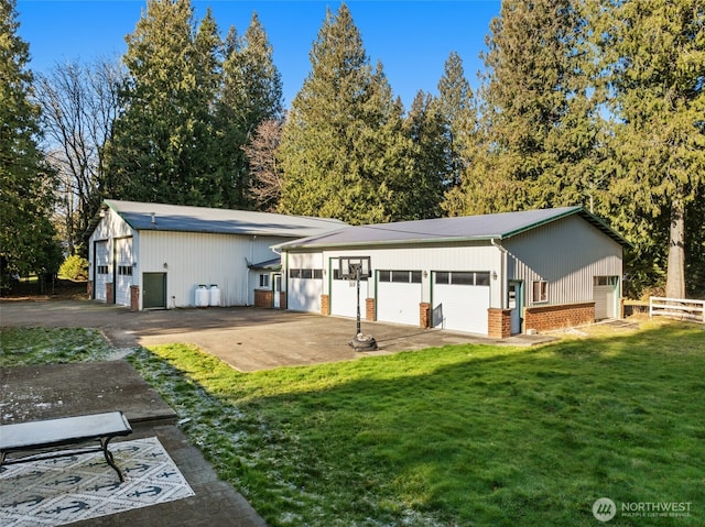 exterior space with brick siding, fence, a lawn, a garage, and an outbuilding