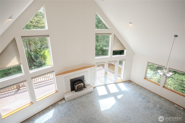 19002 20th St NW, Lakebay, WA 98349 - unfurnished living room with high vaulted ceiling, a wood stove, carpet flooring, and a chandelier