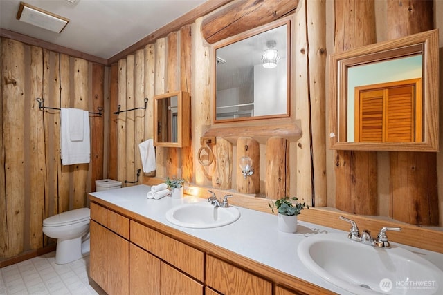 full bathroom featuring double vanity, wood walls, toilet, and a sink