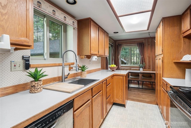 kitchen with a sink, appliances with stainless steel finishes, brown cabinetry, and light countertops