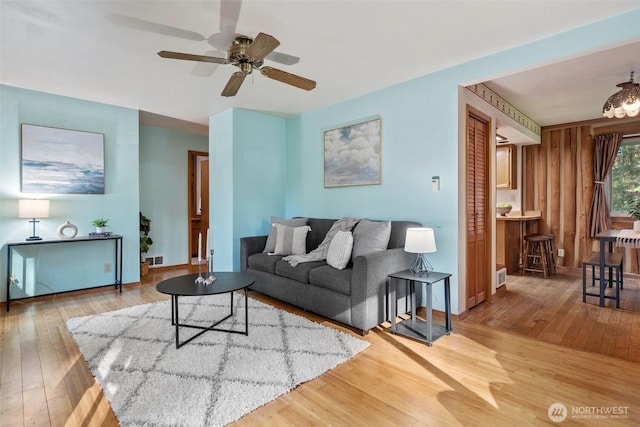 living room with visible vents, baseboards, a ceiling fan, and hardwood / wood-style floors