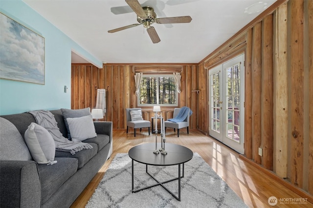 living area featuring a ceiling fan, wooden walls, and wood finished floors