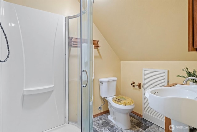 bathroom with toilet, a stall shower, a sink, baseboards, and vaulted ceiling