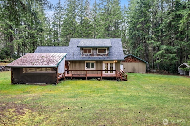 rear view of property with a deck, a shingled roof, and a yard