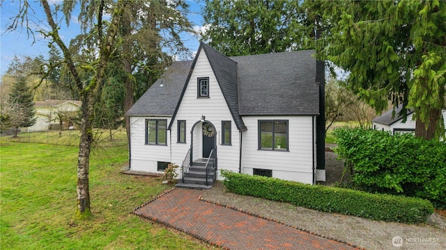 view of front of property featuring entry steps, a front lawn, fence, and roof with shingles