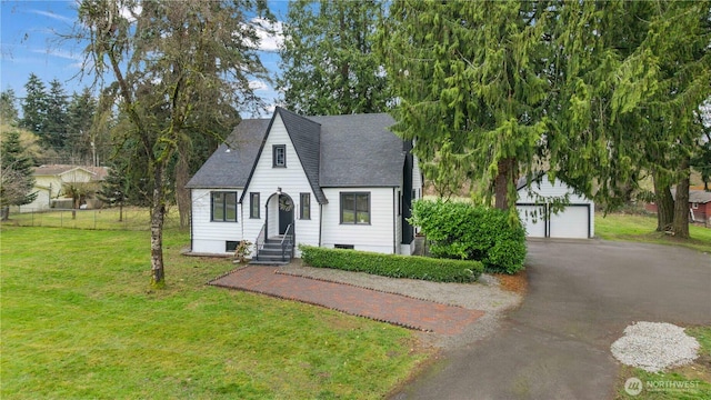 view of front of home with driveway, a front lawn, entry steps, roof with shingles, and a garage