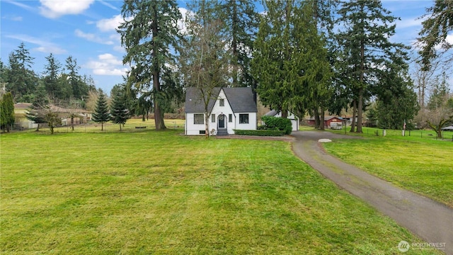 view of front facade featuring aphalt driveway, fence, and a front lawn