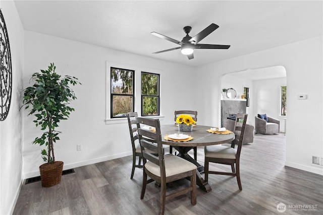 dining space with baseboards, arched walkways, and dark wood-type flooring