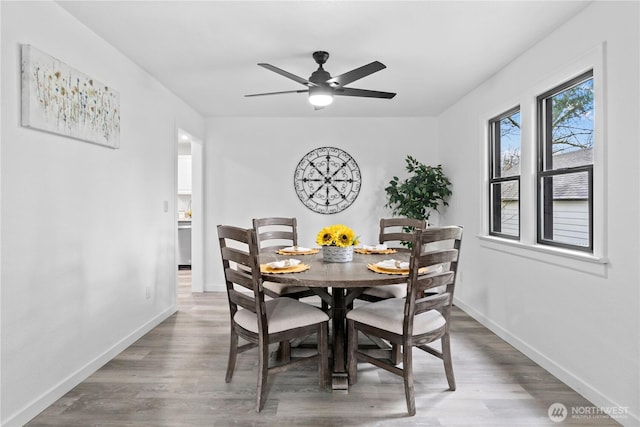 dining room featuring wood finished floors, baseboards, and ceiling fan