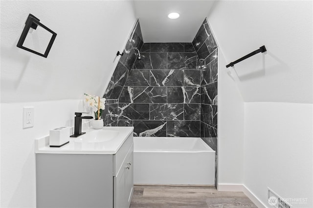 full bathroom with vanity, wood finished floors, visible vents, lofted ceiling, and shower / bathing tub combination