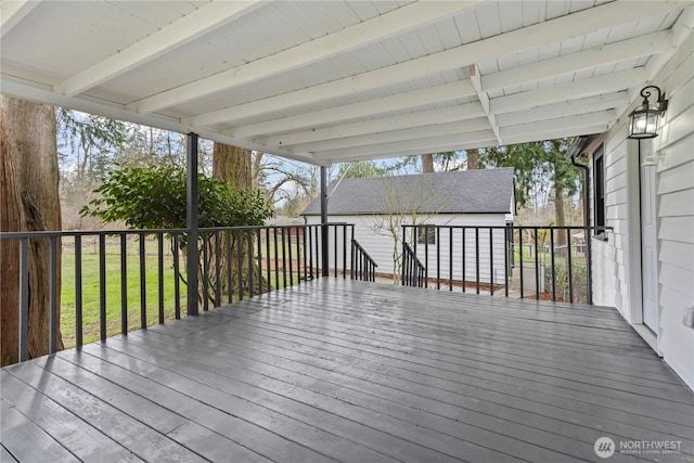 wooden deck with an outdoor structure and a lawn