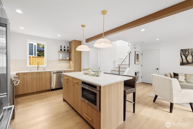 kitchen featuring modern cabinets, a sink, a kitchen breakfast bar, wall oven, and dishwasher