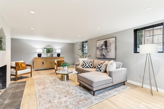 living area featuring recessed lighting, a brick fireplace, baseboards, and wood finished floors