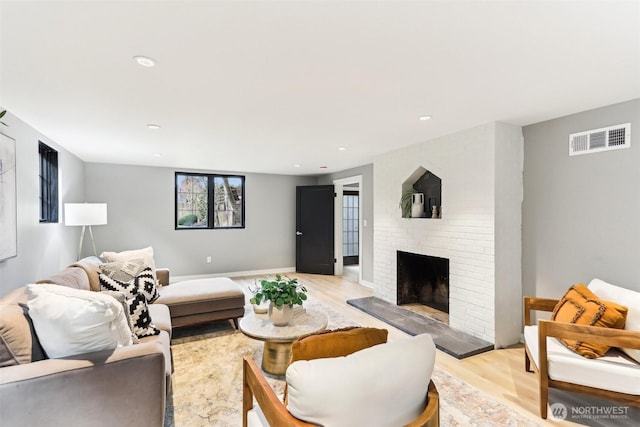 living room featuring recessed lighting, visible vents, a brick fireplace, and light wood-style flooring