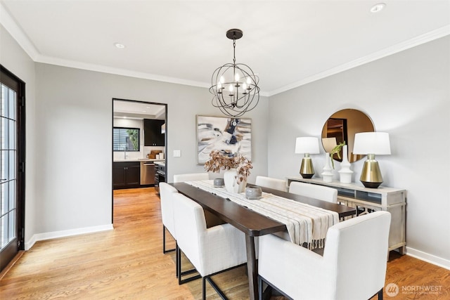 dining space featuring a notable chandelier, light wood-style floors, baseboards, and ornamental molding