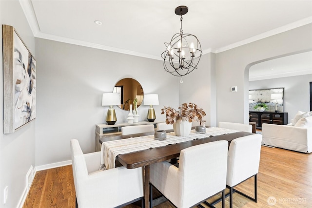 dining area featuring a notable chandelier, wood finished floors, arched walkways, and ornamental molding