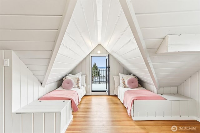 bedroom with vaulted ceiling, access to outside, light wood-style floors, and wood walls