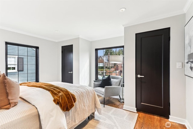 bedroom featuring light wood-style flooring, baseboards, and ornamental molding