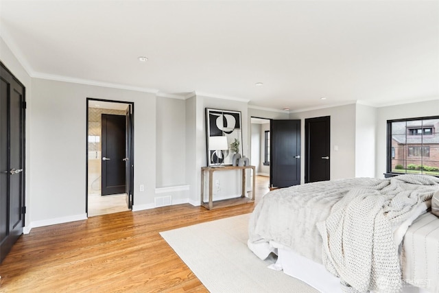 bedroom with visible vents, light wood-type flooring, baseboards, and ornamental molding