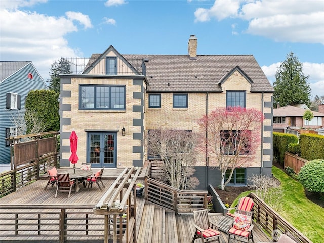 back of house featuring a deck, french doors, brick siding, and a chimney