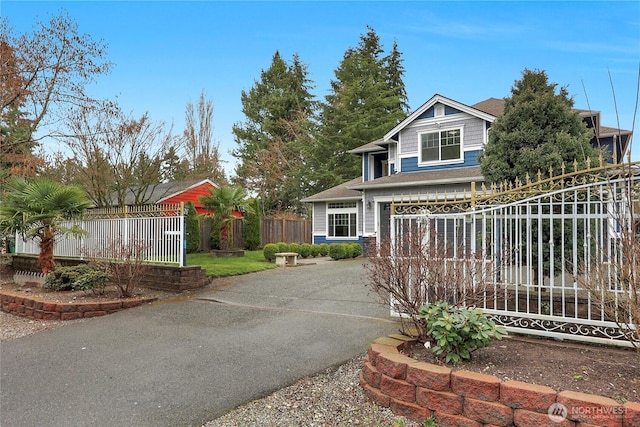 view of front of home featuring an attached garage, fence, driveway, and roof with shingles