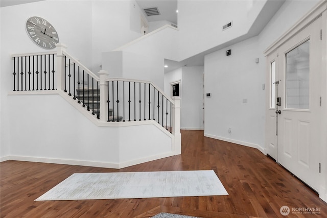 entrance foyer featuring stairs, wood finished floors, visible vents, and baseboards